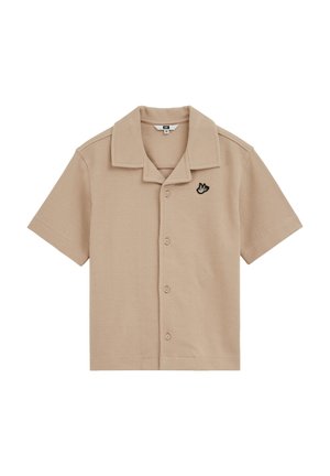 Chemise beige à manches courtes avec boutons, col pointu et un petit oiseau brodé en noir et blanc sur la poitrine gauche.