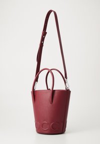 Red textured leather bucket bag with two top handles and adjustable shoulder strap; embossed logo on the front. Circular base.
