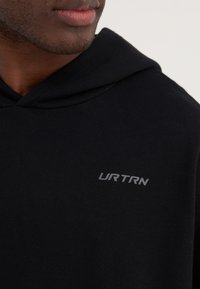 Hoodie noir avec une texture douce, arborant un logo "URTRN" gris sur la poitrine et une capuche avec cordon de serrage. Design simple et moderne.