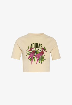 Beiger, kurzärmliger Crop-Sweatshirt mit einem bunten Motiv aus pinkfarbenen Papageien und grünen Blättern sowie dem Schriftzug "ADIDAS" in schwarzer Schrift.
