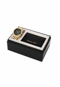 Gouden metalen horloge met zwarte wijzerplaat, Romeinse cijfers, chronograaffuncties, vergezeld van een zwarte nepleren kaarthouder, gepresenteerd in een doos.