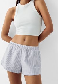 Vit ribbad croptopp kombinerad med ljusblå och vitrandiga shorts med resårmidja och två framknappar.
