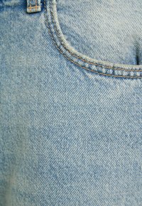 Light blue denim jeans with a faded texture, featuring a front pocket and contrasting stitching along the seams.