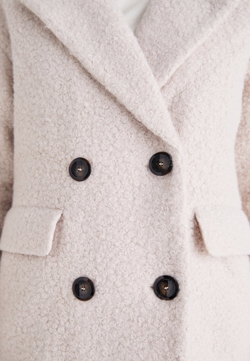 Hellrosa, zweireihige Jacke aus strukturiertem Stoff, mit großen schwarzen Knöpfen, aufgesetzten Revers und seitlichen Taschen.