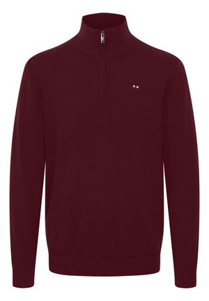 Burgundijas puloveris ar pusi-zip apkakli, ribinātām piedurknēm un apakšmalu, ar mazu logotipu ar sarkaniem, baltajiem un ziliem akcentiem uz krūšu daļas.