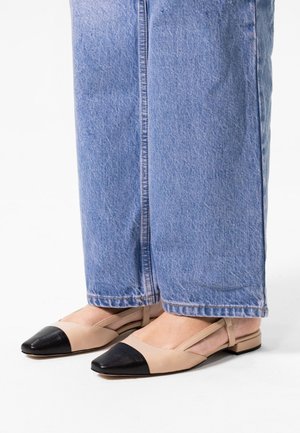 Beige en zwarte slingback ballerina's met een spitse neus, gemaakt van een gladde stof en met een lage hak, gecombineerd met lichtblauwe wijduitlopende jeans.