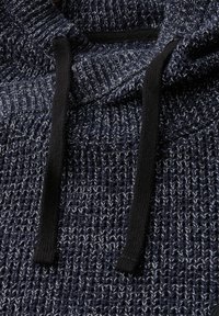 Stickad tröja i mörkblått med ljusblåa inslag, med en huva, svarta dragsnören och ett strukturerat vävmönster.