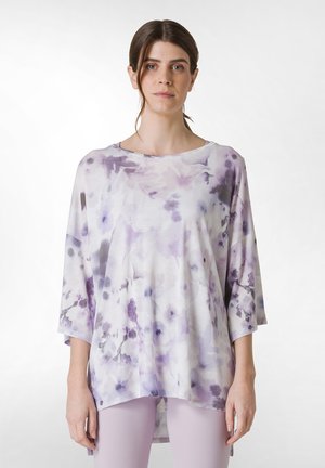 Løs pasform, kortærmet top lavet af letvægtsstof i hvid, med et purpurfarvet blomstermønster og rund halsudskæring.