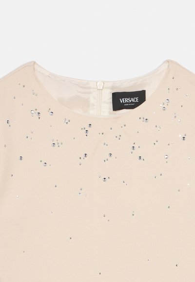 Μπεζ φόρεμα Versace με στρογγυλή λαιμόκοψη και διάσπαρτα μικρά ασημένια παγέτα, με φερμουάρ και ετικέτα της μάρκας στο εσωτερικό της λαιμόκοψης.