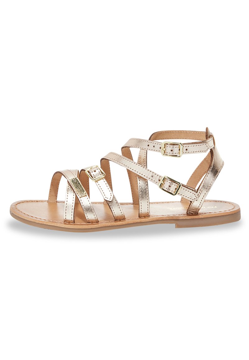 Sandalia de tiras en rosa dorado metálico con múltiples correas y detalles de hebilla. Suela plana, diseño de punta abierta y acabado de cuero texturizado.