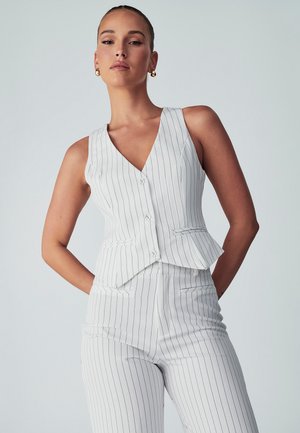White pinstripe vest with a deep V-neck, button closure, and matching slim-fit trousers, featuring a peplum accent and minimalistic design.