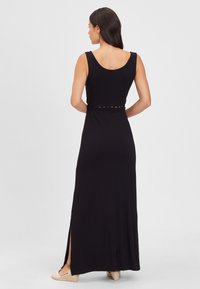 Black maxi dress with a sleeveless design, cut-out detail at the waist, and side slits, made from smooth, stretchy fabric.