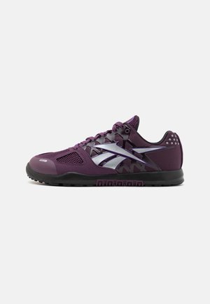 Baskets de sport violettes avec semelle noire, dessus en mesh, lacets et logo argenté sur le côté, vues de l'extérieur sur fond blanc.