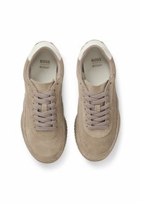 Beżowe zamszowe sneakersy na sznurówki z wkładkami amortyzującymi marki "BOSS Ortholite", przedstawione z widoku z góry na białym tle.