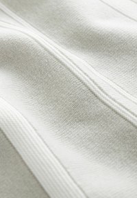 Tessuto grigio chiaro con una superficie texture, caratterizzato da sottili righe e dettagli cuciti per elementi di design aggiuntivi. Aspetto morbido e liscio.