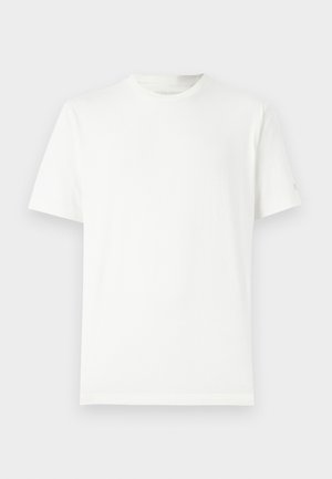 Prosty biały T-shirt z krótkim rękawem i okrągłym dekoltem na jasnoszarym tle, wyłożony płasko, bez zagnieceń i wzorów.