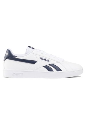 Baskets basses blanches Reebok avec des bandes latérales bleu marine, logo sur le côté et le talon, et lacets blancs sur fond blanc.