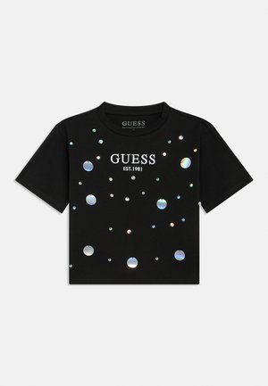Tricou negru cu mâneci scurte, cropt, cu textul „GUESS EST. 1981” și cu mici aplicații holografice circulare strălucitoare împrăștiate pe partea din față.