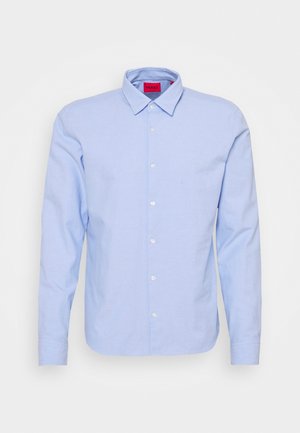 Camisa de vestir azul claro de manga larga con botones, cuello puntiagudo y una etiqueta roja en el interior del cuello.