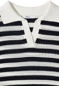 Polo tricoté à rayures blanches et bleu marine avec un col ouvert et une étiquette "CECIL" à l'intérieur de l'encolure.
