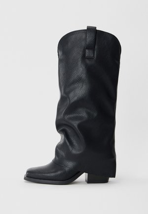 Stivali da cowboy in pelle nera con un design morbido, punta quadrata e tacco basso. Presenta un tassello sul retro per una facile calzata.