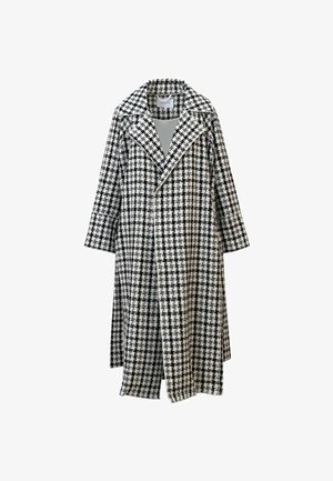 Lang kåpe i svart-hvitt rutemønster med brede slag og en enkelspent front, vist mot en hvit bakgrunn.