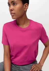 Roze crewneck t-shirt van zacht katoen. Korte mouwen en een relaxte pasvorm. De stof heeft een gladde textuur en een effen kleur zonder patronen.