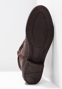 Brun läderkänga med en texturerad sula, rund tå och dekorativ söm. Storlek 37 märkt på hälen.