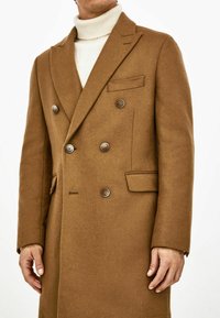 Brauner, doppelt knopfbarer Mantel aus weicher Wolle, mit zwei vorderen Taschen, sechs Knöpfen und einer taillierten Passform mit Revers.