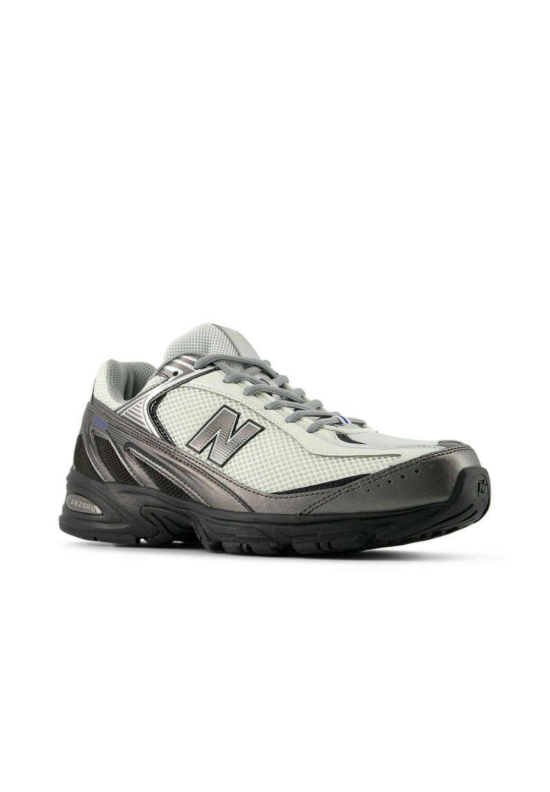 Scarpe sportive grigie e bianche con tomaia in mesh, colletto imbottito e logo "N" ben visibile. Suola testurizzata per presa e stabilità, punta rinforzata.