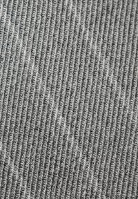 Artimas pilkos megztos medžiagos vaizdas, kuriame matyti vertikali juostelė su smulkiomis, vienodomis siūlėmis ir nedidelėmis tekstūros variacijomis.