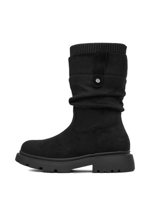 Czarny zamszowy but sięgający do połowy łydki, z prążkowanym mankietem, suwakiem, grubą, wytrzymałą podeszwą i zaokrąglonym noskiem, pokazany z boku, skierowany w lewo.