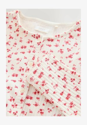 Biała bluzka z kwiecistym wzorem w odcieniach różu. Posiada okrągły dekolt, zapięcie na guziki oraz teksturowany prążkowany design.