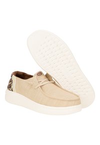 Chaussures en tissu beige avec un dessus texturé, doublure marron, accent imprimé léopard au talon et semelle en caoutchouc blanc avec un motif en vague.