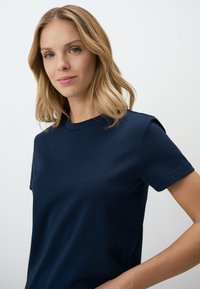 T-shirt in cotone blu navy con scollatura rotonda e maniche corte, texture liscia e design aderente. Stile semplice e minimalista.