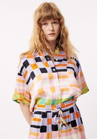 Knoopshirt en rok set met een kleurrijke gecheckte patroon in tinten van roze, oranje, zwart en groen; lichte stof met korte mouwen.