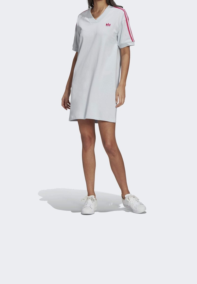 Lichtgrijze katoenen jurk met korte mouwen, V-hals en roze streepaccenten. Bevat een klein logo op de borst en heeft een ruime pasvorm.