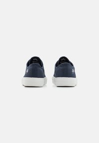 Marine kanvas sneakers med hvite gummisåler, rund tå og brodert logo på hælen; lav toppdesign med teksturert stoff.