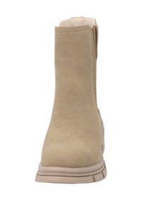 Botines de ante beige con un acabado suave, cremallera lateral y suela de goma de color claro. Detalle de costura a lo largo del borde superior.