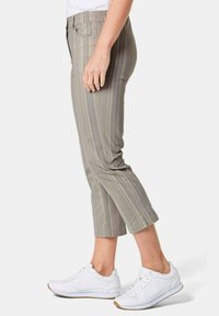 Lichtgrijze gestreepte cropped broek met een platte voorkant, zijzakken en een slanke pasvorm, gecombineerd met witte sneakers. Glad stofoppervlak.