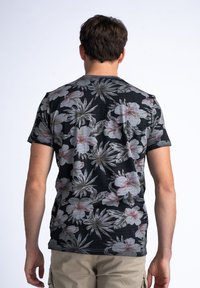Camiseta negra de manga corta con un estampado floral en tonos de gris y rosa. Presenta un cuello redondo y un corte relajado. Tejido texturizado.