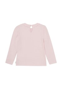 Långärmad, ljusrosa skjorta med rund halsringning, en nyckelhålsknäppning bak och subtila volanger längs kragen.