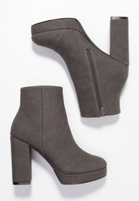 Harmaat korkeat nilkkurit, joissa on sileä tekonahkainen pinta, korkoalustat ja sivuvetoketju, varustettuna paksulla lohkarejalkapohjalla.