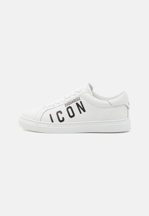 Hvite skinnsko med flat såle, med svart "ICON" tekst og merke logo. Glatt tekstur, avrundet tå, og snøring med øyeledd.