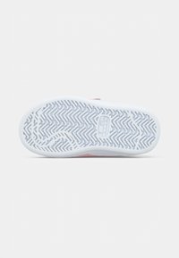 White rubber shoe sole with zigzag tread pattern and circular logo. Soft pink and gray accents near the upper edge. Smooth texture.