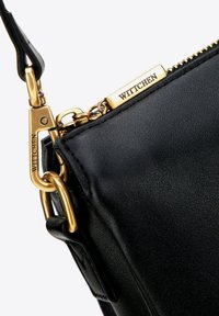 Borsa a tracolla in pelle nera con finitura testurizzata, hardware dorato e un tirazip con il marchio "WITTCHEN". Gli accenti includono un gancio a moschettone.
