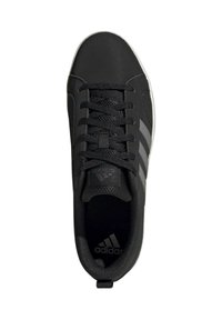 Zapatilla negra con un material liso, tres rayas grises y una suela de goma blanca. Los cordones son negros con una superficie texturizada.