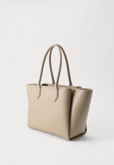 Μπεζ δερμάτινη τσάντα tote με διπλές λαβές, δομημένο ορθογώνιο σχήμα και ελάχιστα ράμματα σε απλό ανοιχτό φόντο.