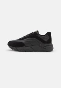 Schwarze Sneakers aus einer Kombination von glattem Leder und Wildleder, mit einer strukturierten Sohle und minimalen Nähten.