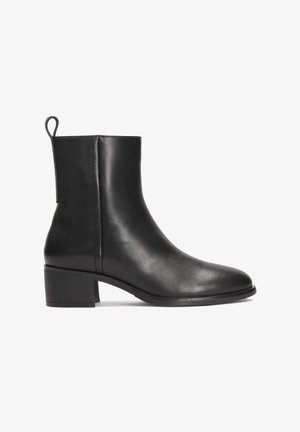 Stivale in pelle nera a caviglia con punta rotonda, tacco a blocco basso, cuciture minimali e una linguetta sul retro per indossarlo facilmente.